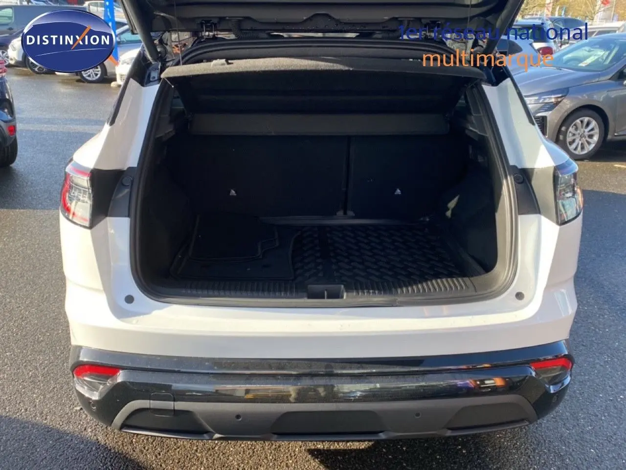 Coffre ouvert en vue arrière d’un Renault Austral blanc nacré avec toit noir, stationné en extérieur.