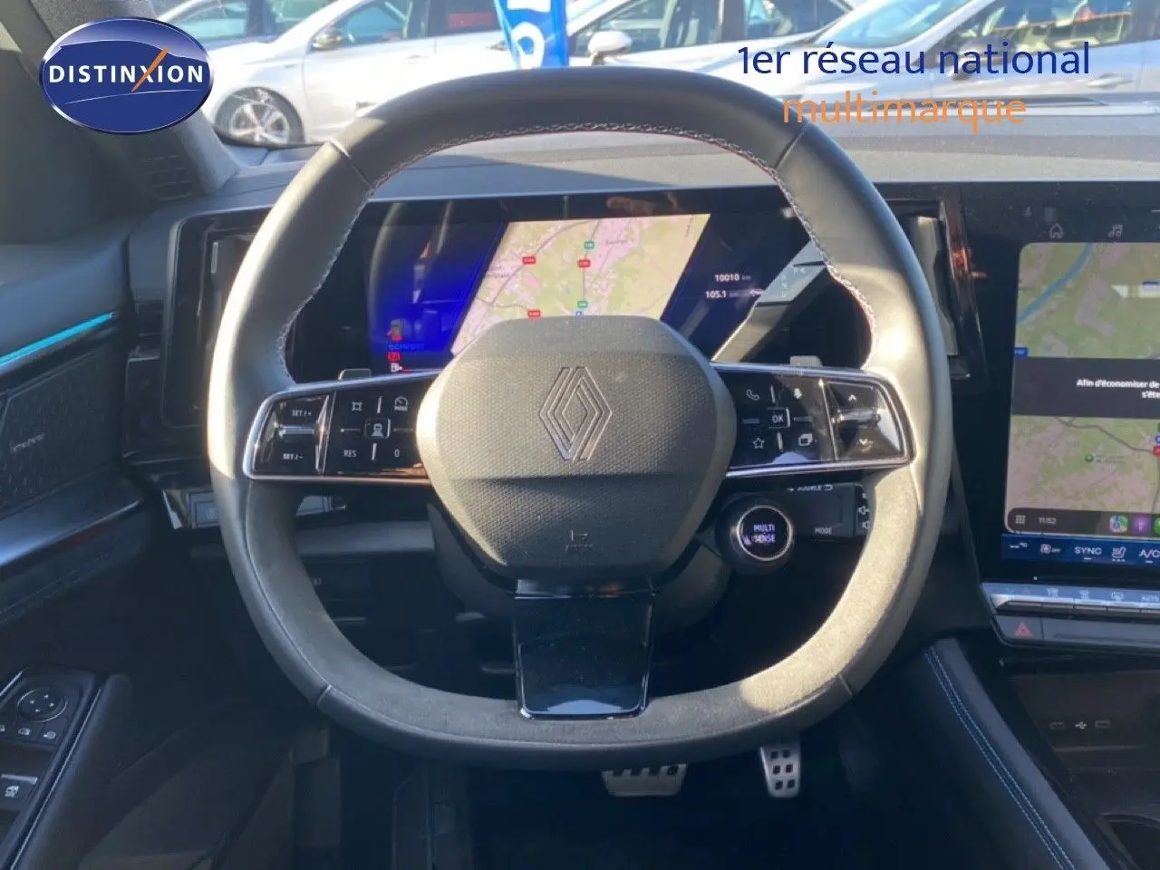 Vue centrée sur le volant du Renault Austral 2024, avec tableau de bord numérique et écran tactile en arrière-plan.