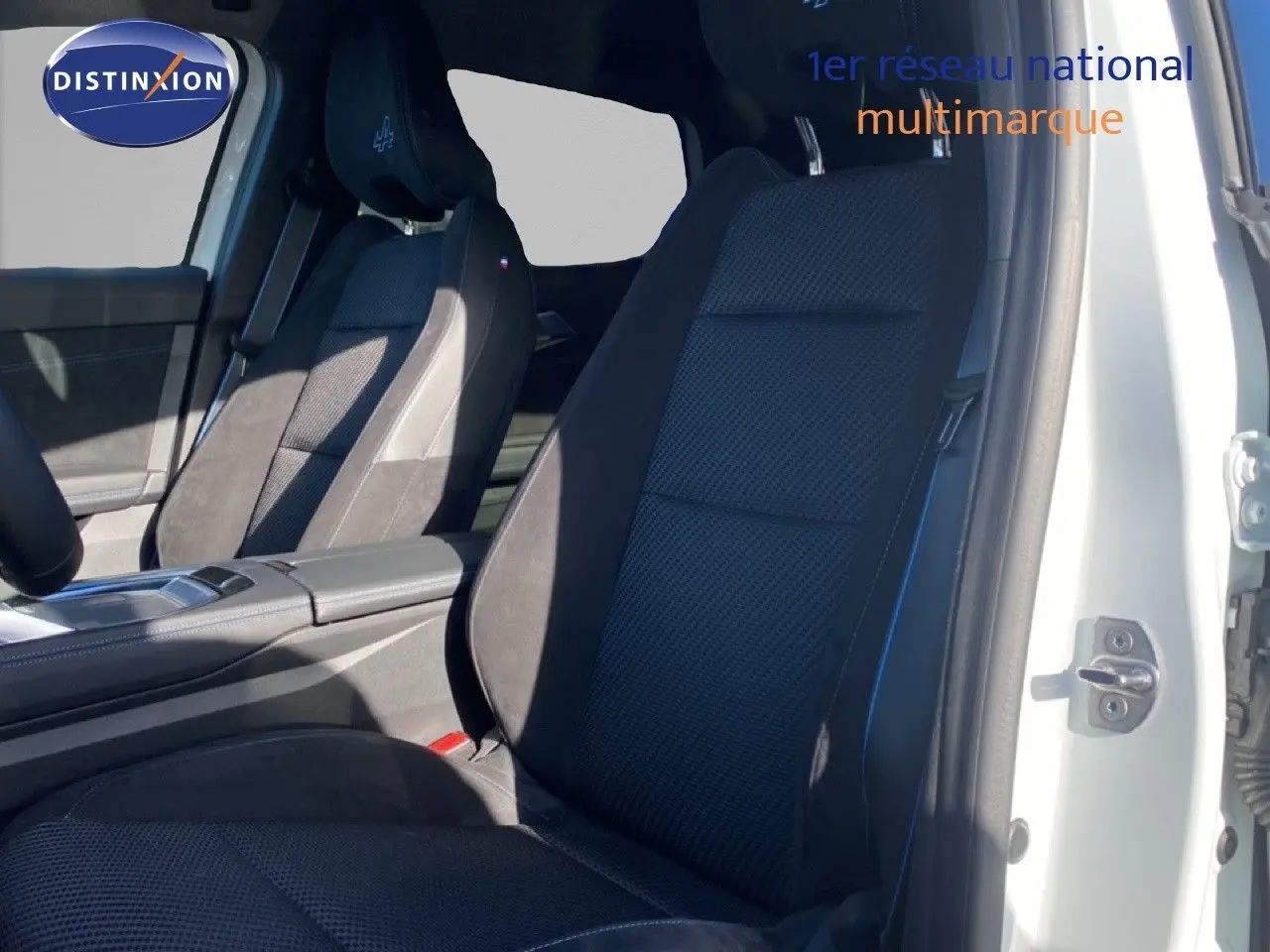 Vue intérieure côté conducteur du Renault Austral 2024 blanc nacré, sièges noirs avec logo Alpine brodé sur l'appuie-tête.