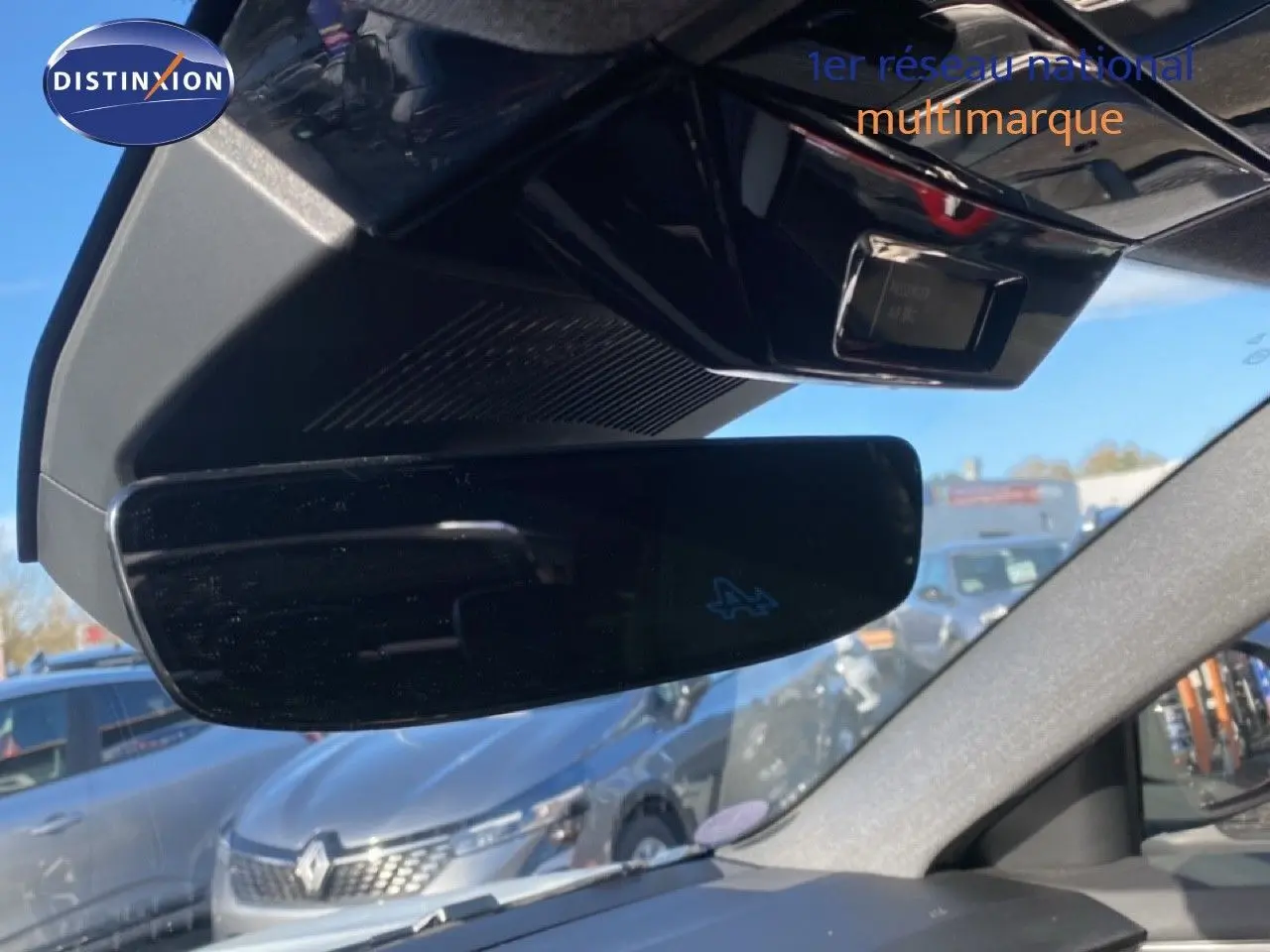 Rétroviseur intérieur noir avec logo Alpine, vue partielle du tableau de bord et extérieur avec Renault Austral blanc nacré.