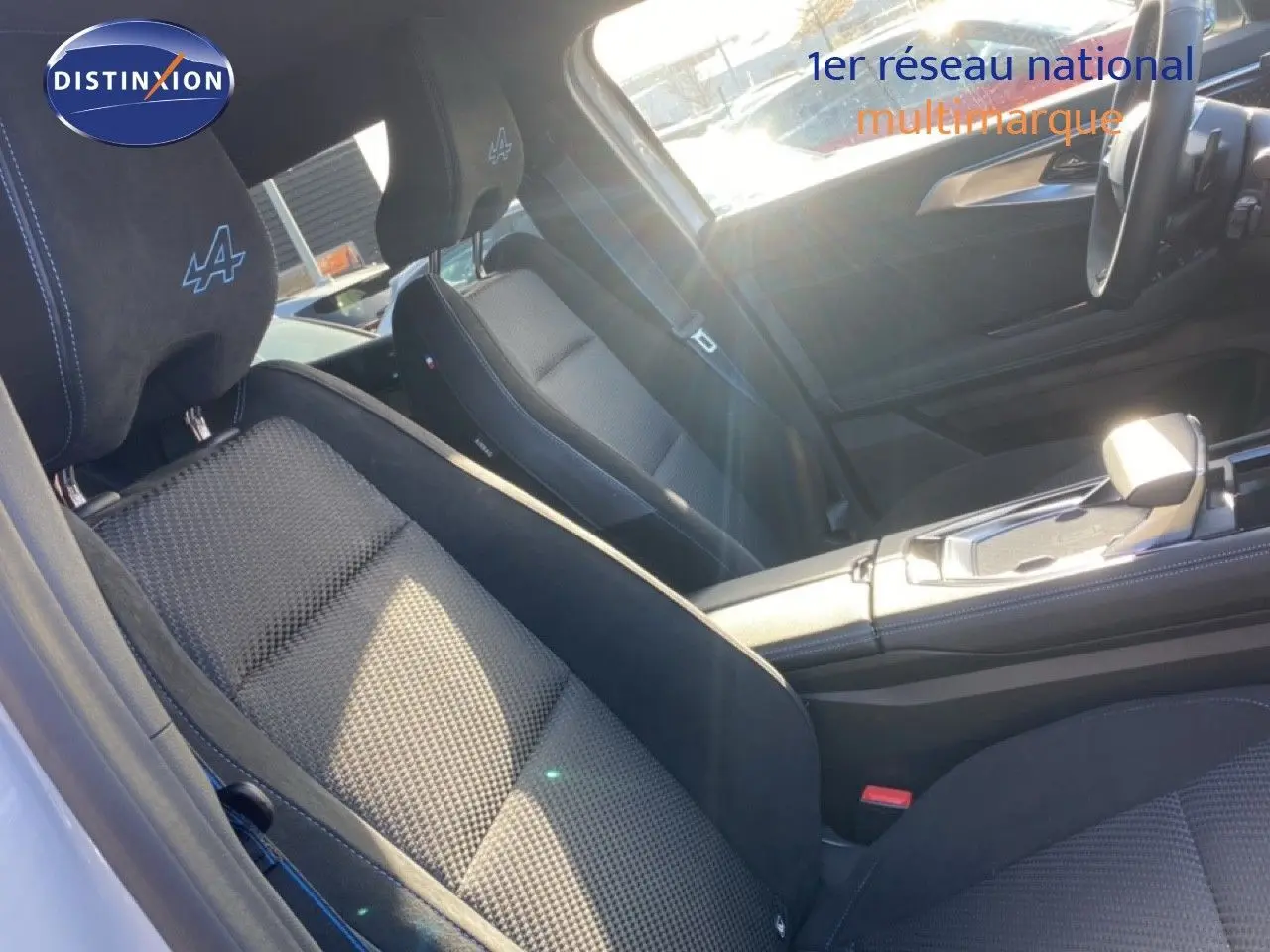 Vue intérieure du siège avant gauche en tissu et alcantara avec logo Alpine sur appuie-tête du Renault Austral blanc nacré.