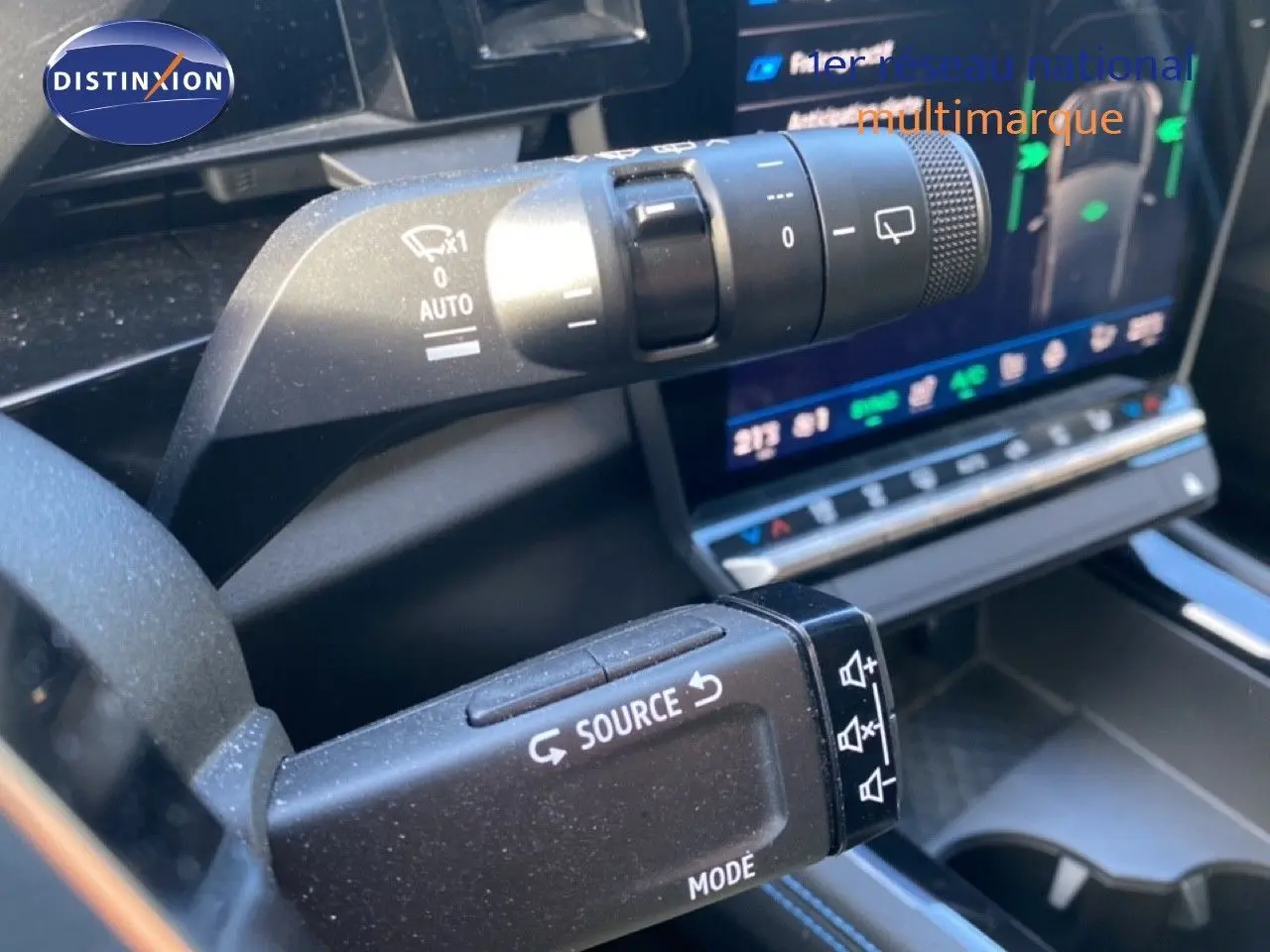 Gros plan sur les commandes au volant du Renault Austral E-Tech blanc nacré avec écran tactile en arrière-plan.