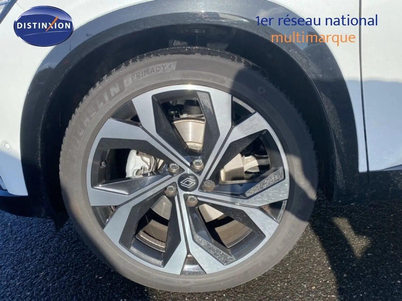 Gros plan sur la roue avant droite du Renault Austral blanc nacré avec jante alu bicolore design moderne.