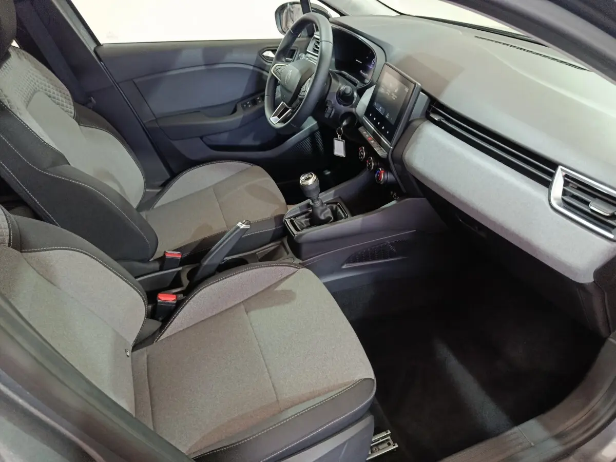 Vue intérieure côté conducteur de la Renault Clio gris clair 2025, avec tableau de bord moderne et boîte manuelle.