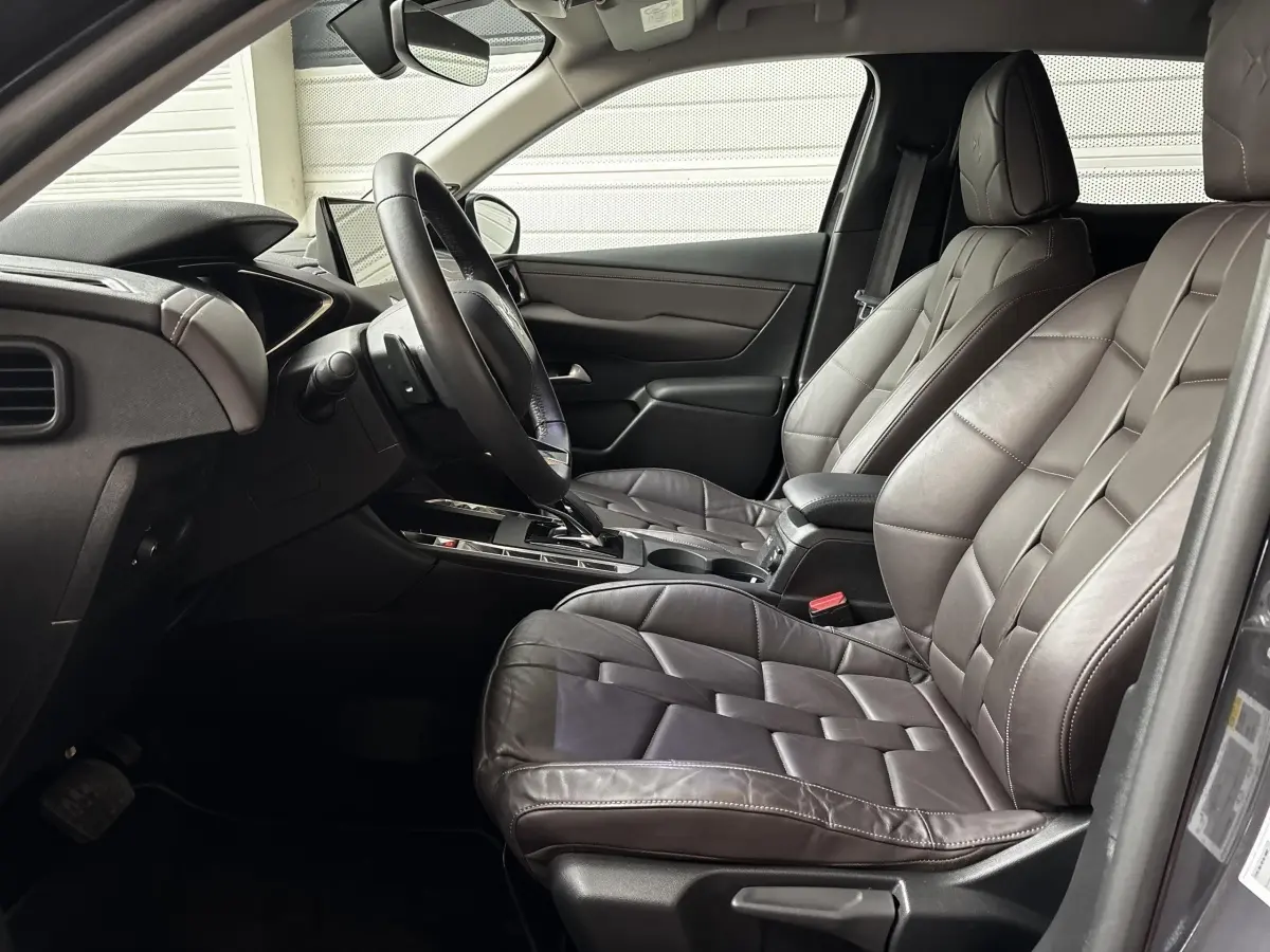 Vue intérieure côté conducteur du DS3 2024, sièges en cuir gris foncé avec volant multifonctions et console centrale moderne.