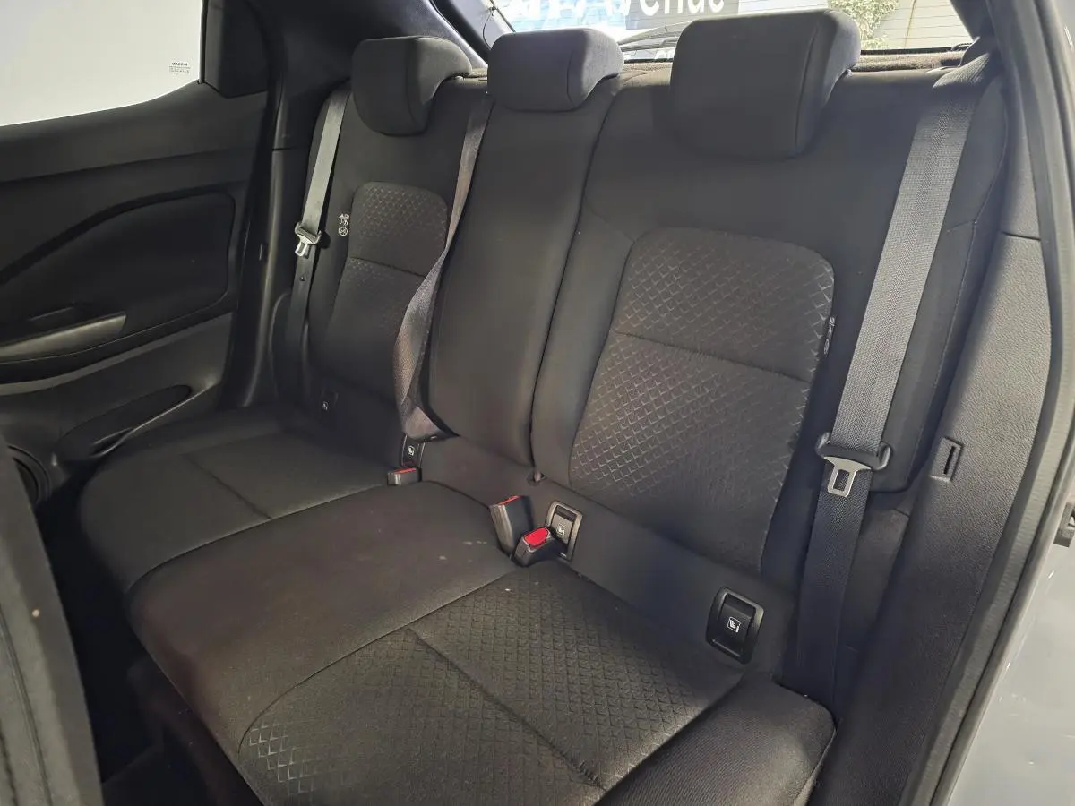 Vue intérieure de la banquette arrière noire du Nissan Juke 2023 avec trois appuis-tête réglables et ceintures de sécurité.