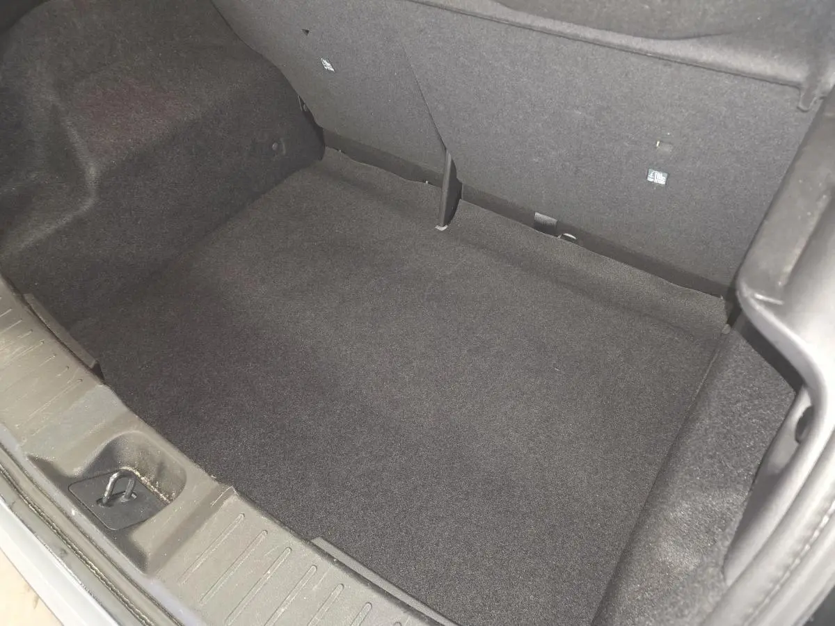 Coffre spacieux de Nissan Juke gris 2023 vu de dessus, avec revêtement intérieur noir et crochet de fixation.