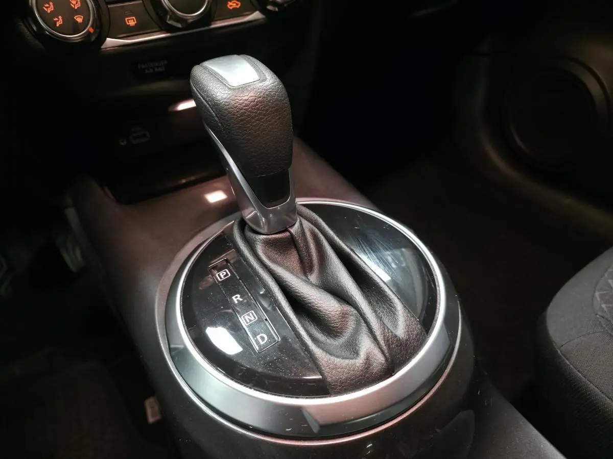 Gros plan sur le levier de vitesses automatique noir et argenté dans l’habitacle du Nissan Juke gris 2023.