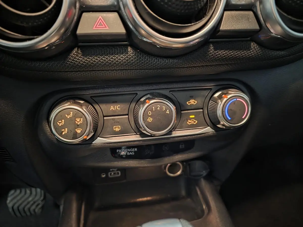 Vue rapprochée des commandes de climatisation et ventilation du tableau de bord noir du Nissan Juke 2023 gris.