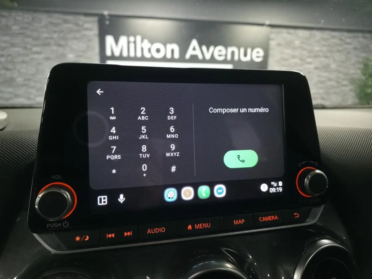 Écran tactile central du Nissan Juke 2023 affichant le clavier de composition, avec commandes audio et bouton caméra.