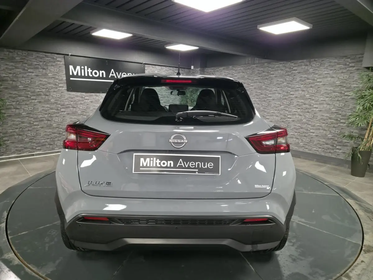 Vue arrière d'un Nissan Juke gris métallisé 2023 avec feux LED et toit noir en showroom.