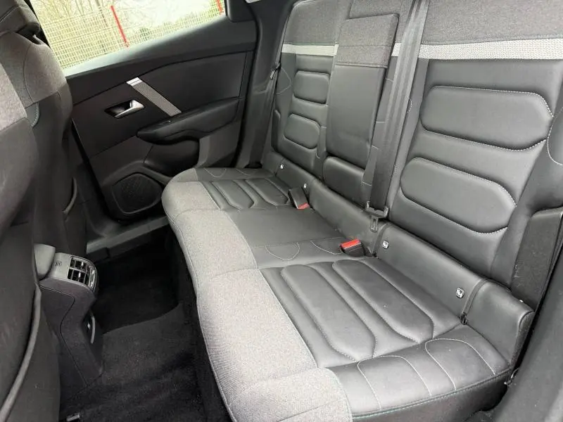 Vue intérieure arrière côté droit du Citroën C4 X 2024 gris, montrant les sièges bi-matière cuir et tissu avec ceinture de sécurité.
