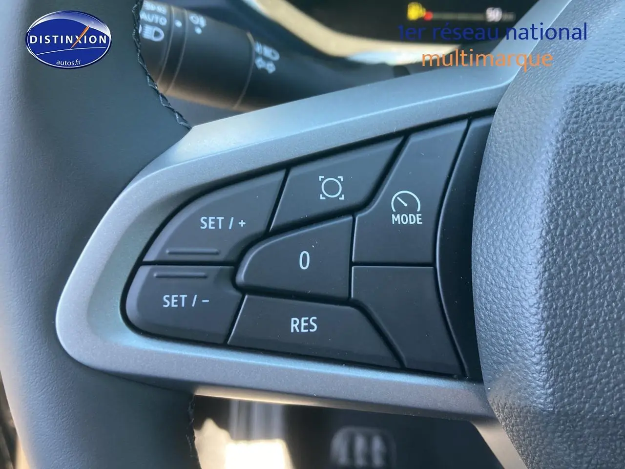 Gros plan sur les commandes multifonctions noires du volant du Dacia Duster 2025, avec boutons de réglage et mode.