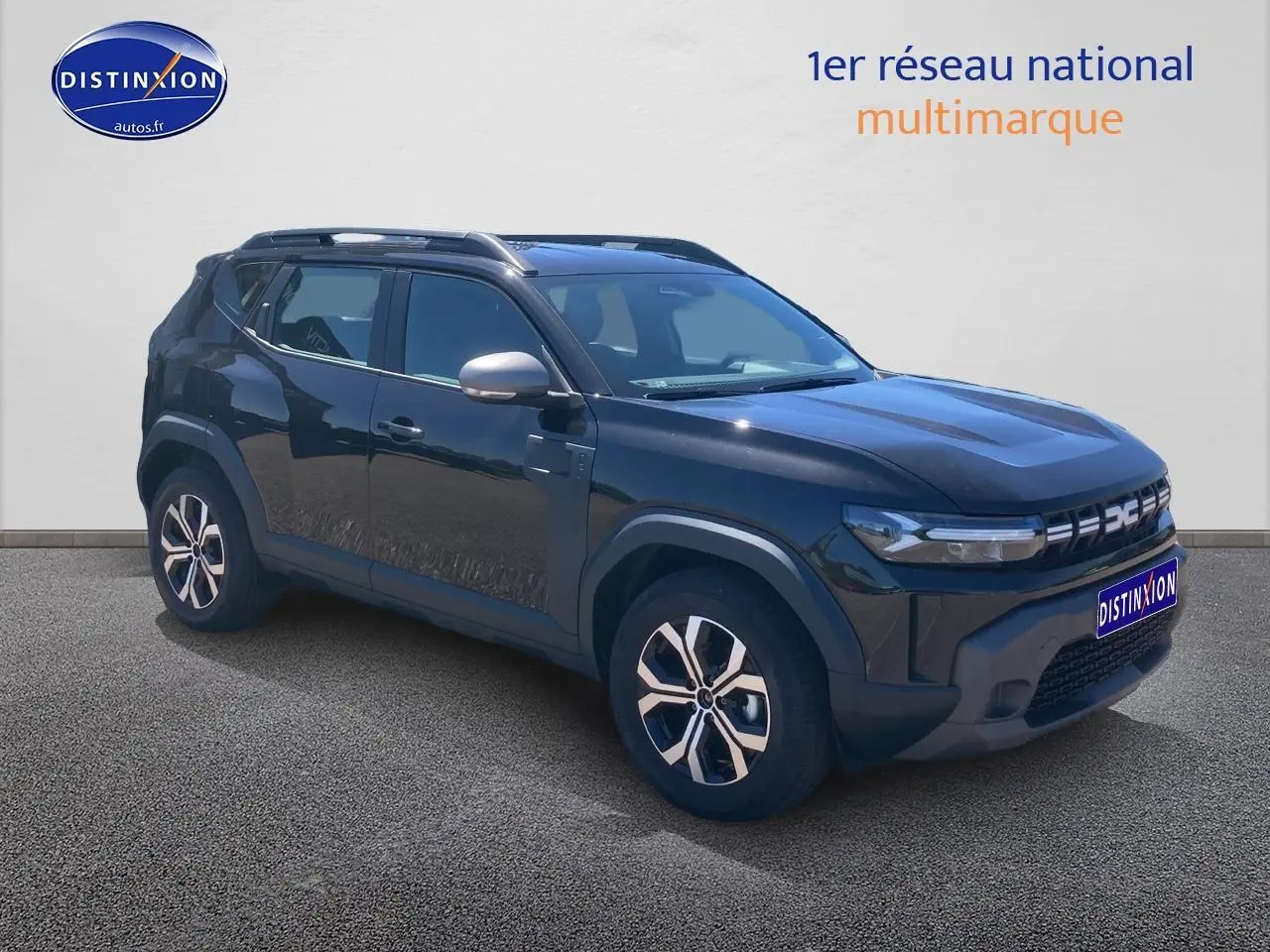 SUV Dacia Duster noir vu en 3/4 avant droit, avec jantes alu et barres de toit visibles.
