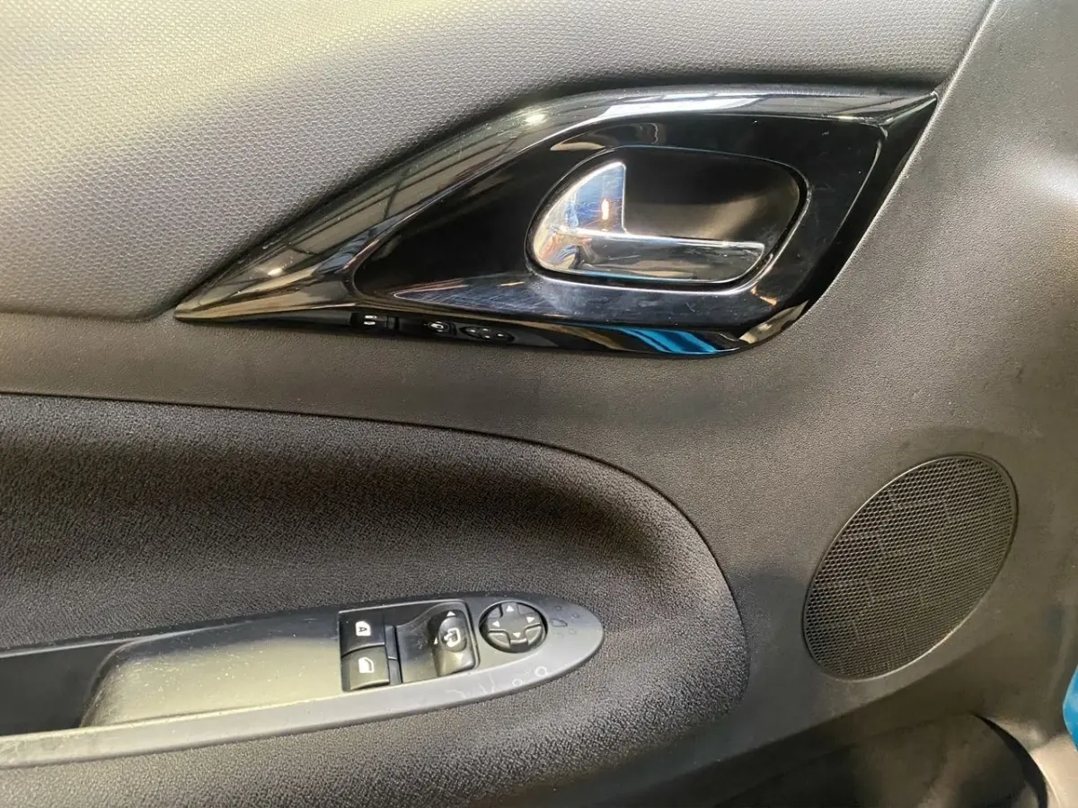 Gros plan sur la poignée intérieure et les commandes de fenêtre de la porte avant gauche d'une Citroën DS3 bleu 2011.