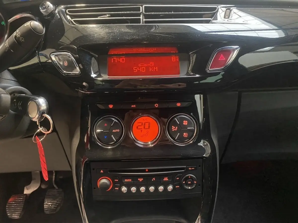 Vue rapprochée du tableau de bord noir brillant de la Citroën DS3 e-HDi, avec affichage digital rouge et commandes climatisation.