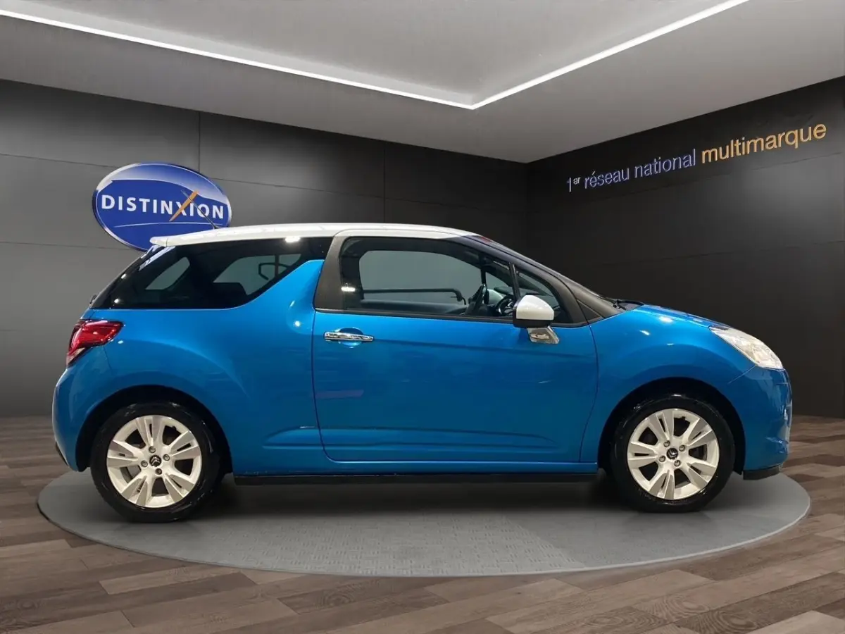 Profil droit d'une Citroën DS3 e-HDi 90 Airdream So Chic bleu avec toit blanc et jantes alliage en showroom.