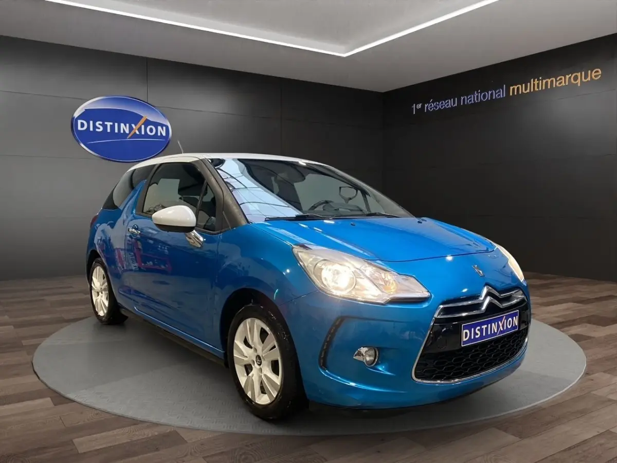 Citroën DS3 e-HDi 90 bleu en 3/4 avant droit avec phares allumés et rétroviseurs blancs contrastants.