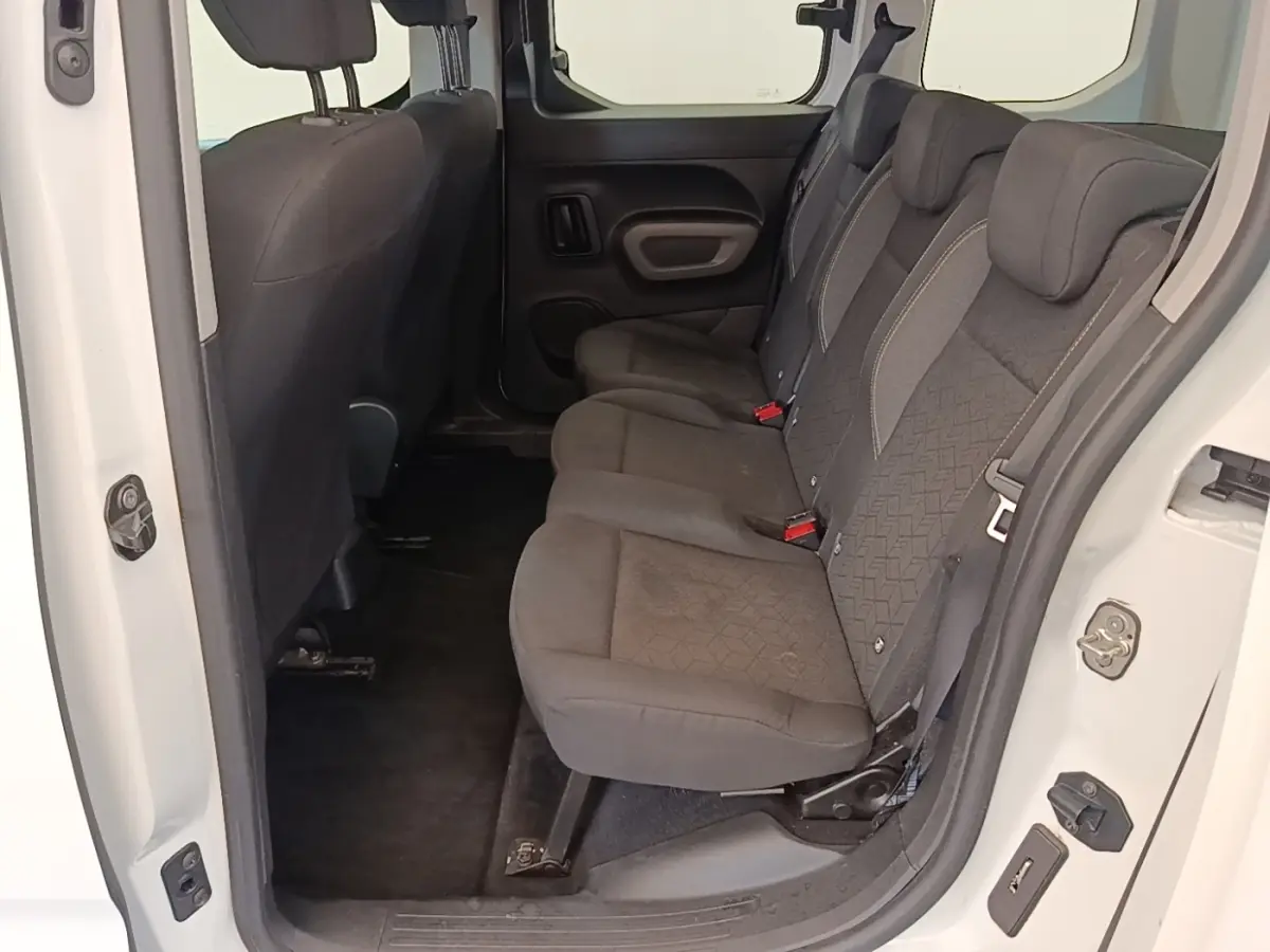 Vue intérieure côté droit sur la banquette arrière noire du Peugeot Rifter blanc, montrant les sièges 3 places et la porte ouverte.