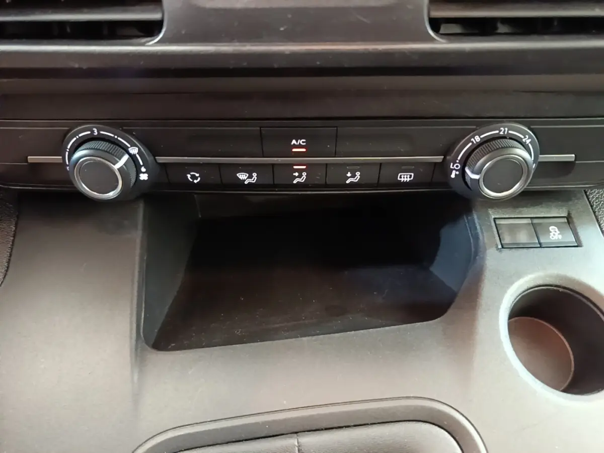 Vue rapprochée de la console centrale noire du Peugeot Rifter 2020, avec commandes de climatisation et rangement.