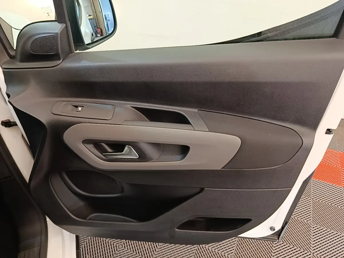 Vue intérieure de la porte avant gauche blanche du Peugeot Rifter 2020, avec poignée et commandes de vitre visibles.