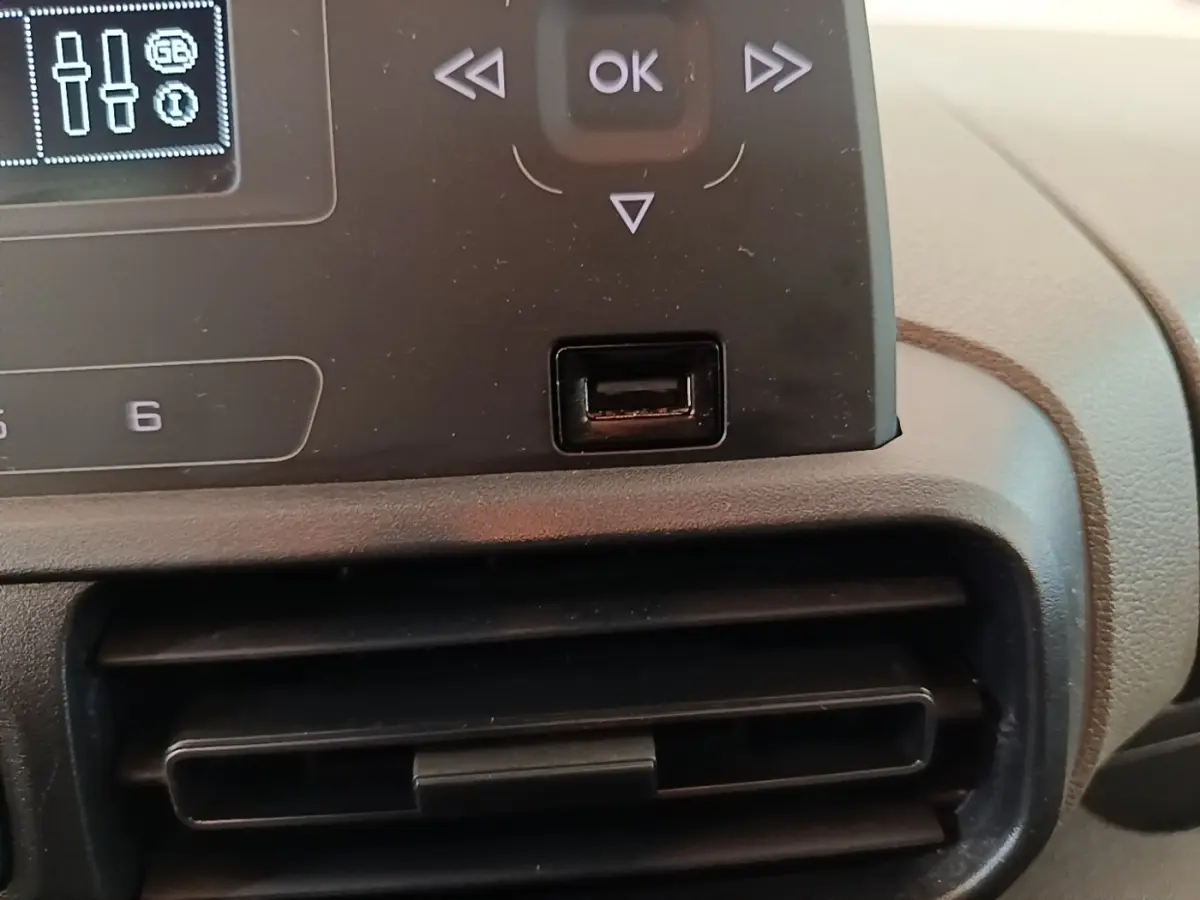 Gros plan sur la console centrale noire du Peugeot Rifter blanc, montrant les commandes et une prise USB.
