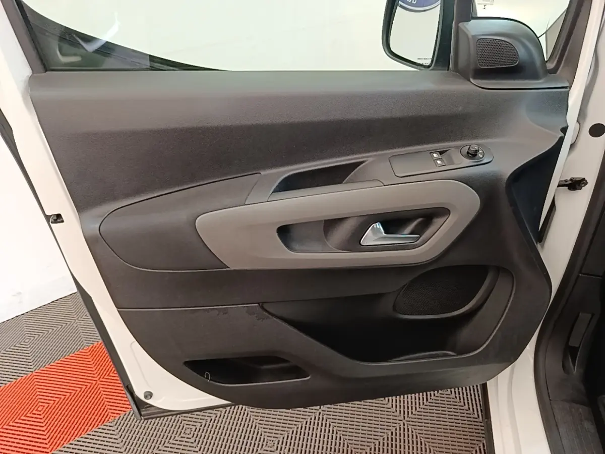 Vue rapprochée de la porte avant gauche blanche du Peugeot Rifter 2020, avec commandes électriques et poignée grise.