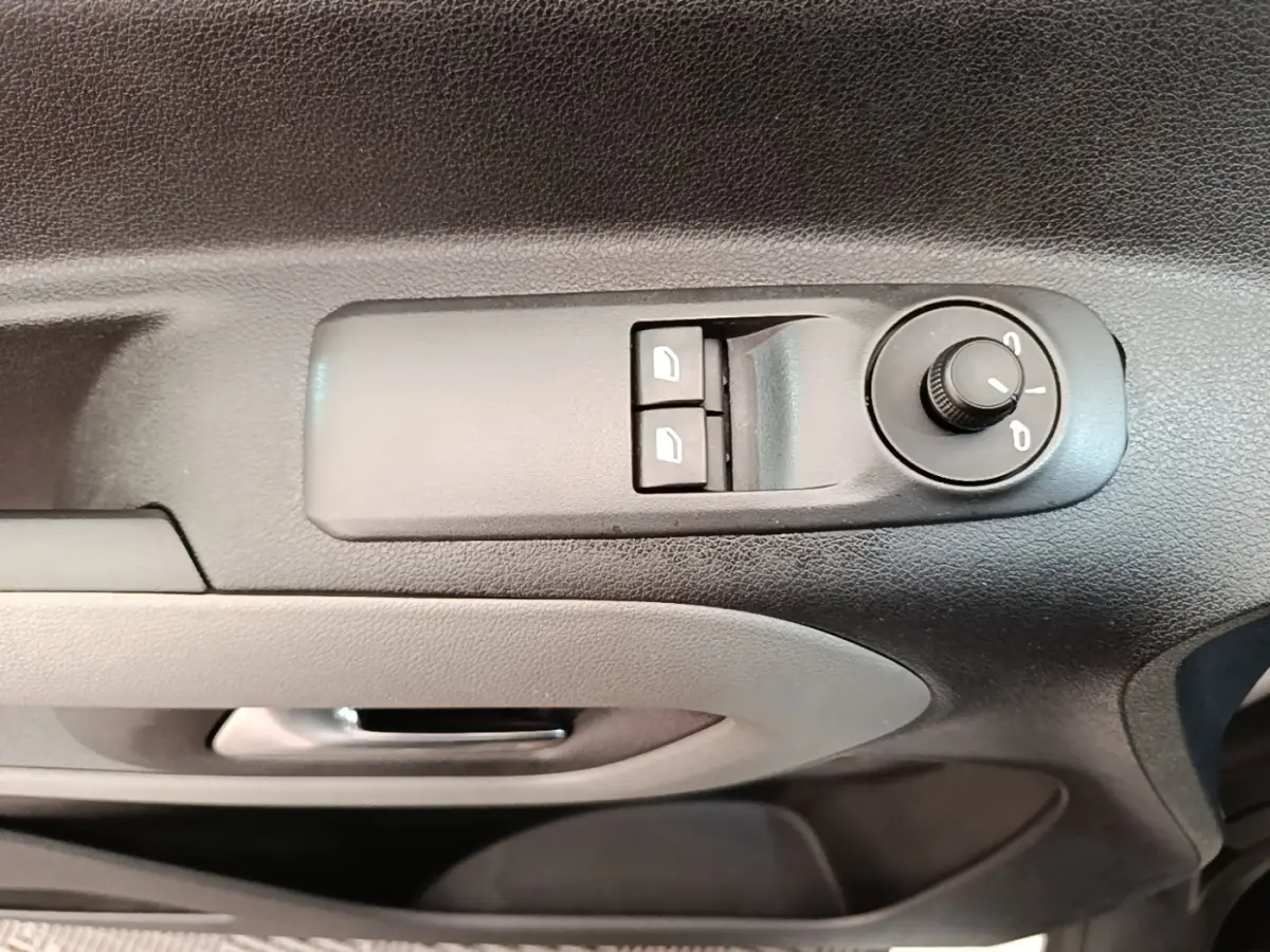 Vue rapprochée des commandes de réglage des rétroviseurs et des vitres côté conducteur d’un Peugeot Rifter blanc.