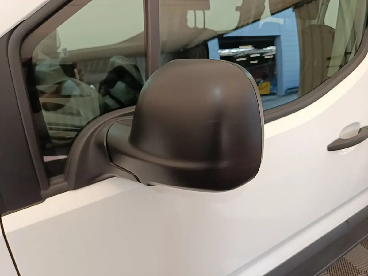 Gros plan sur le rétroviseur noir côté conducteur d’un Peugeot Rifter blanc, vue latérale gauche.
