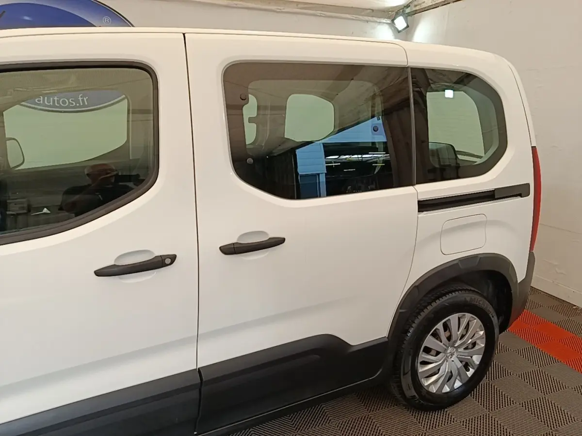 Vue latérale droite d'un Peugeot Rifter blanc, mettant en valeur les grandes fenêtres et les poignées de porte noires.