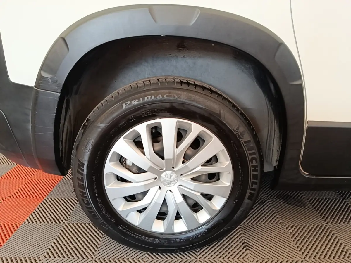 Gros plan sur la roue avant gauche d’un Peugeot Rifter blanc, avec jante argentée et pneu Michelin.