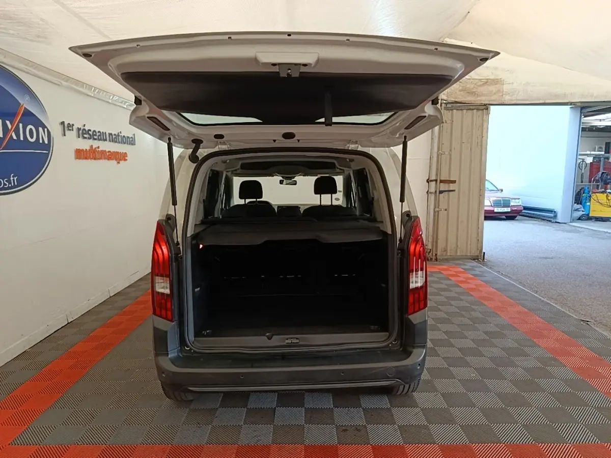Vue arrière d'un Peugeot Rifter blanc 2020 avec hayon ouvert montrant le coffre spacieux et la banquette arrière.