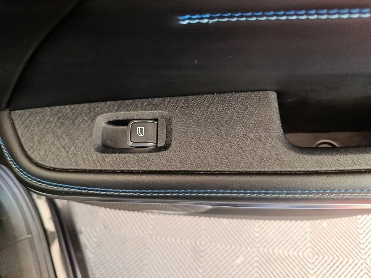 Détail de la commande de lève-vitre sur la portière intérieure avec surpiqûres bleues du LINK & CO 01 Hybride rechargeable.