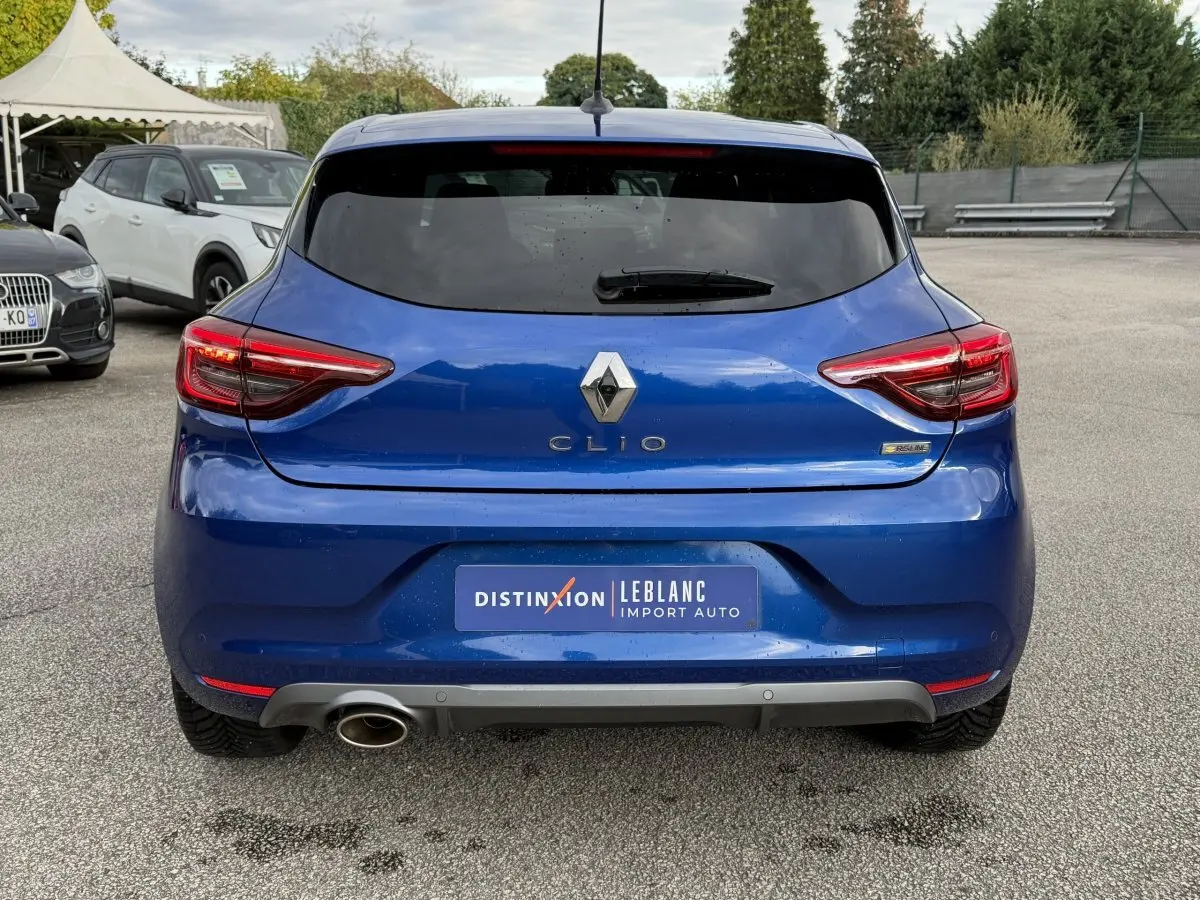 Vue arrière d'une Renault Clio RS Line bleu, avec feux LED et sortie d'échappement chromée visible à gauche.