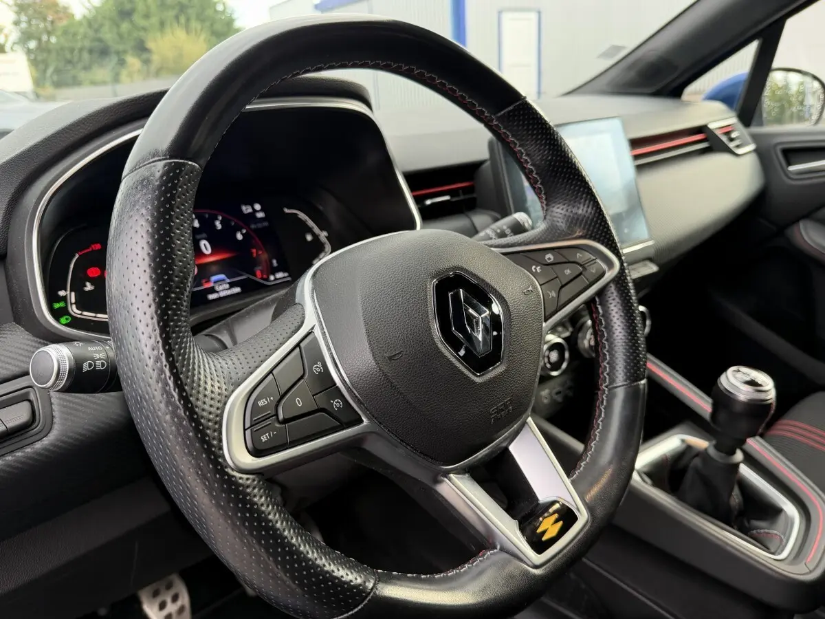 Vue intérieure rapprochée du volant cuir perforé et levier de vitesse manuel de la Renault Clio RS Line bleu 2021.