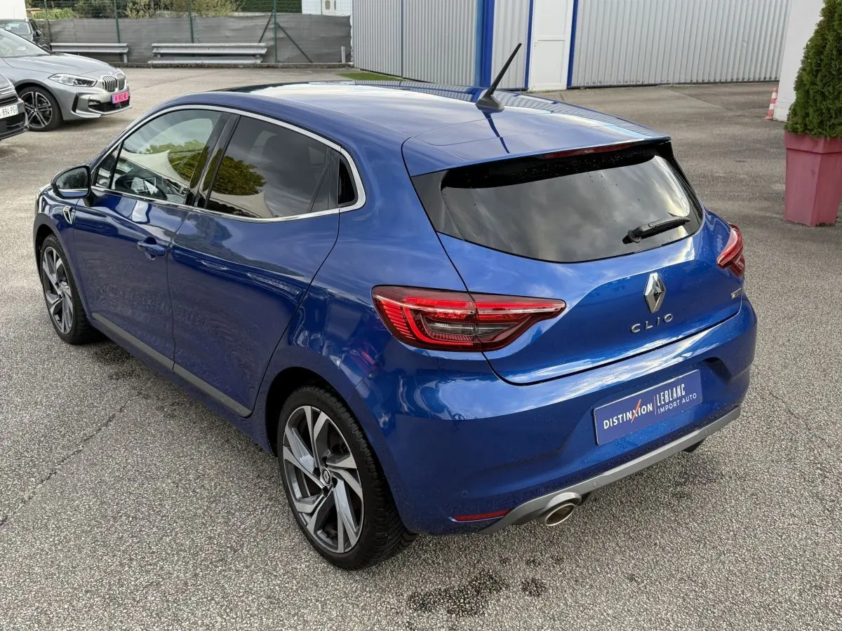 Vue 3/4 arrière droite d'une Renault Clio RS Line bleu 2021 avec jantes alliage et feux LED distinctifs.