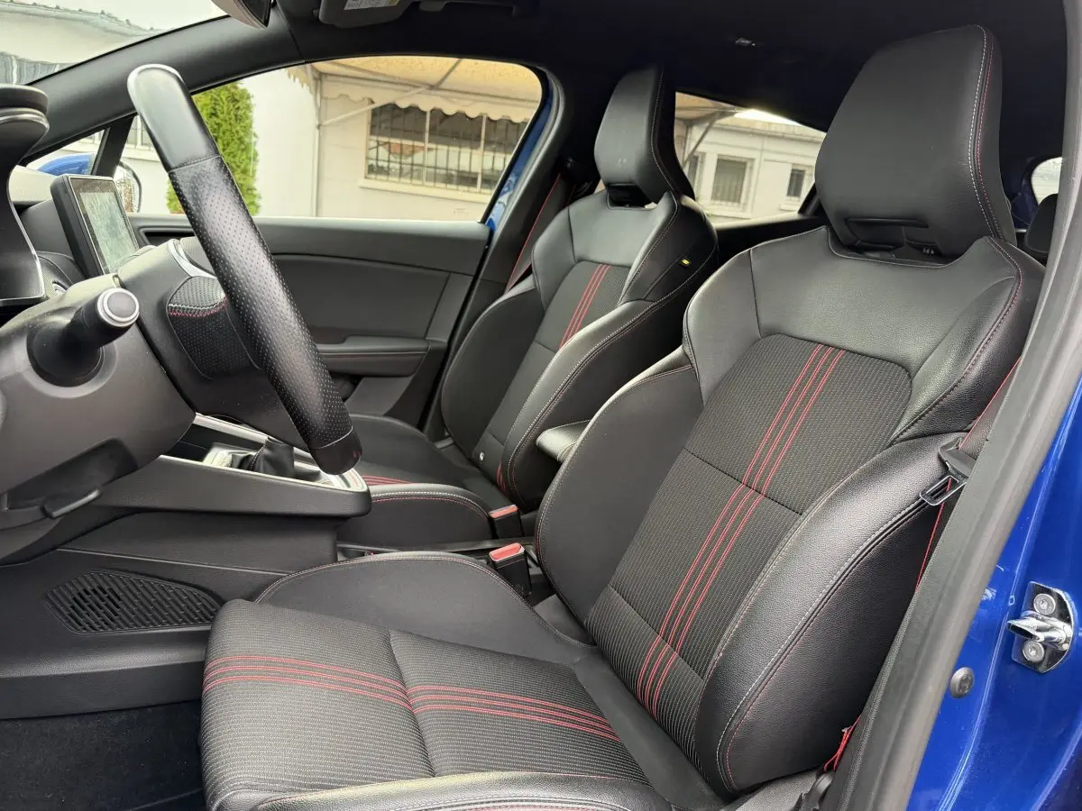 Vue intérieure côté conducteur de la Renault Clio RS Line bleu 2021, sièges sport noirs avec surpiqûres rouges.