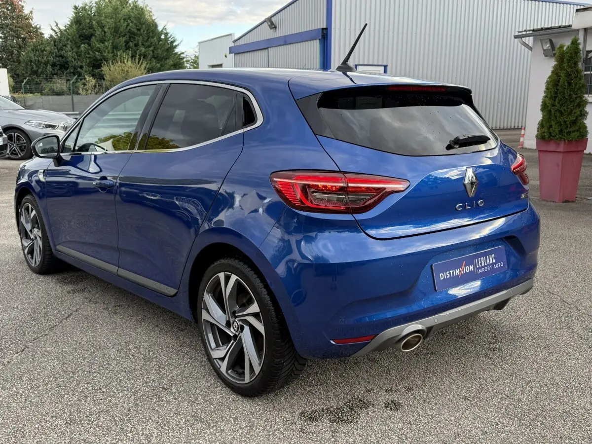 Renault Clio RS Line bleu vue 3/4 arrière droit, feux LED et jantes alliage distinctives visibles.
