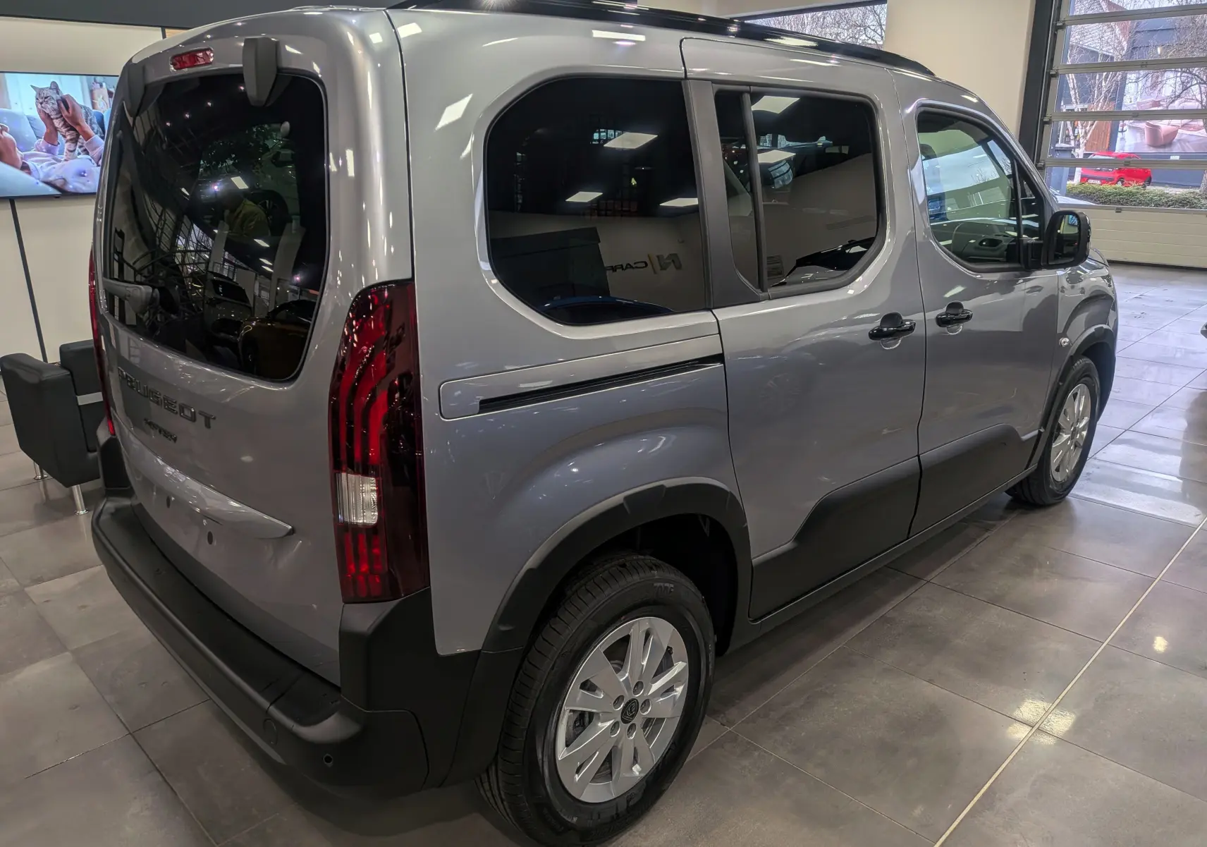 Vue 3/4 arrière droite d'un Peugeot Rifter gris acier 2025 avec vitres teintées et jantes alliage 16 pouces.