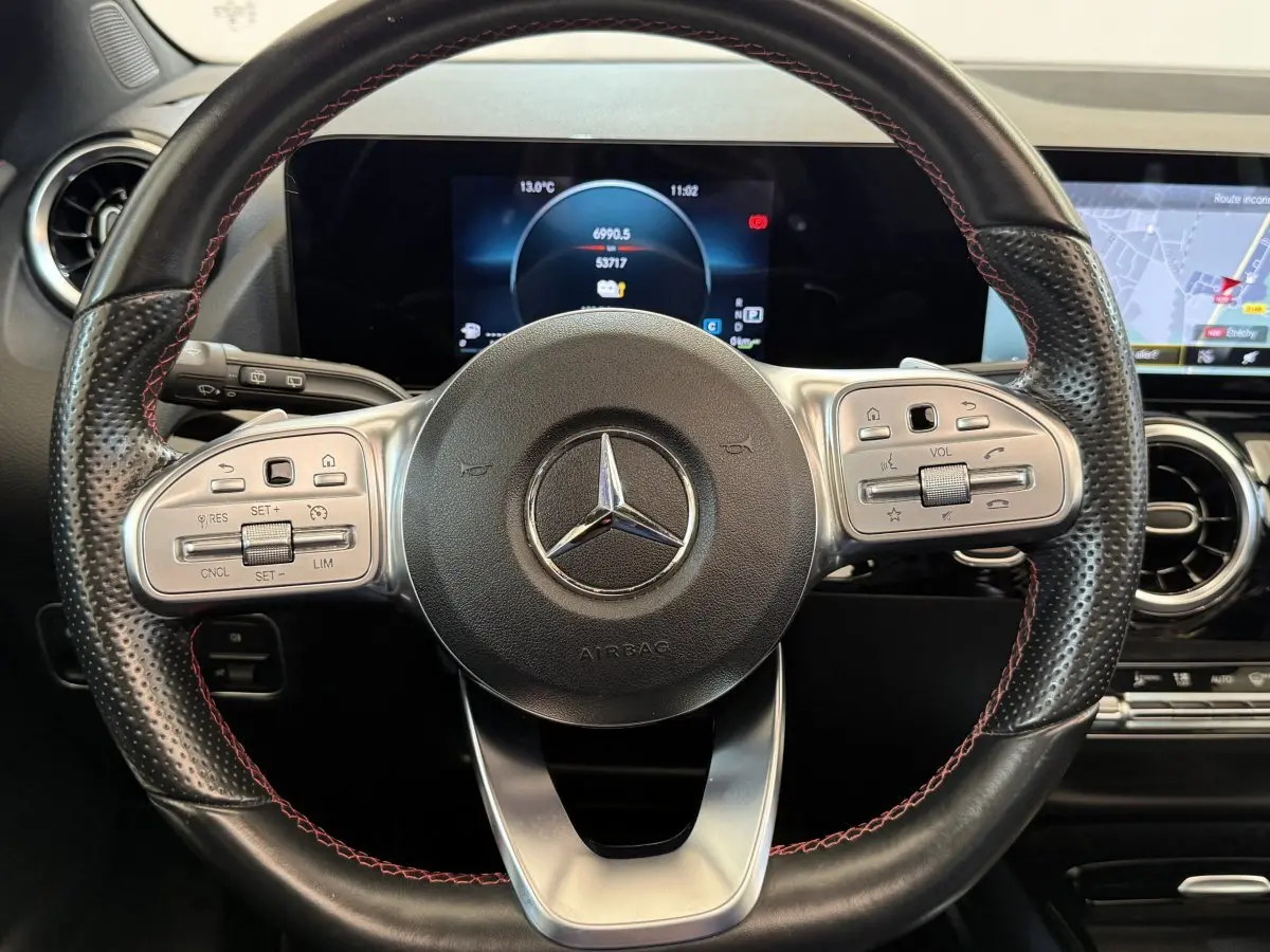 Vue rapprochée du volant cuir noir avec surpiqûres rouges et tableau de bord numérique du Mercedes GLA 250 e AMG Line 2023.