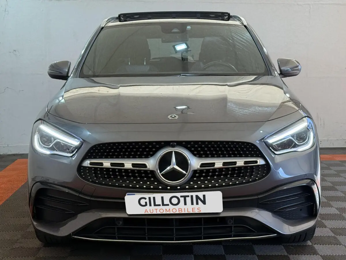 Vue frontale d'une Mercedes GLA 250 e AMG Line 2023 gris clair avec phares LED et calandre diamantée.