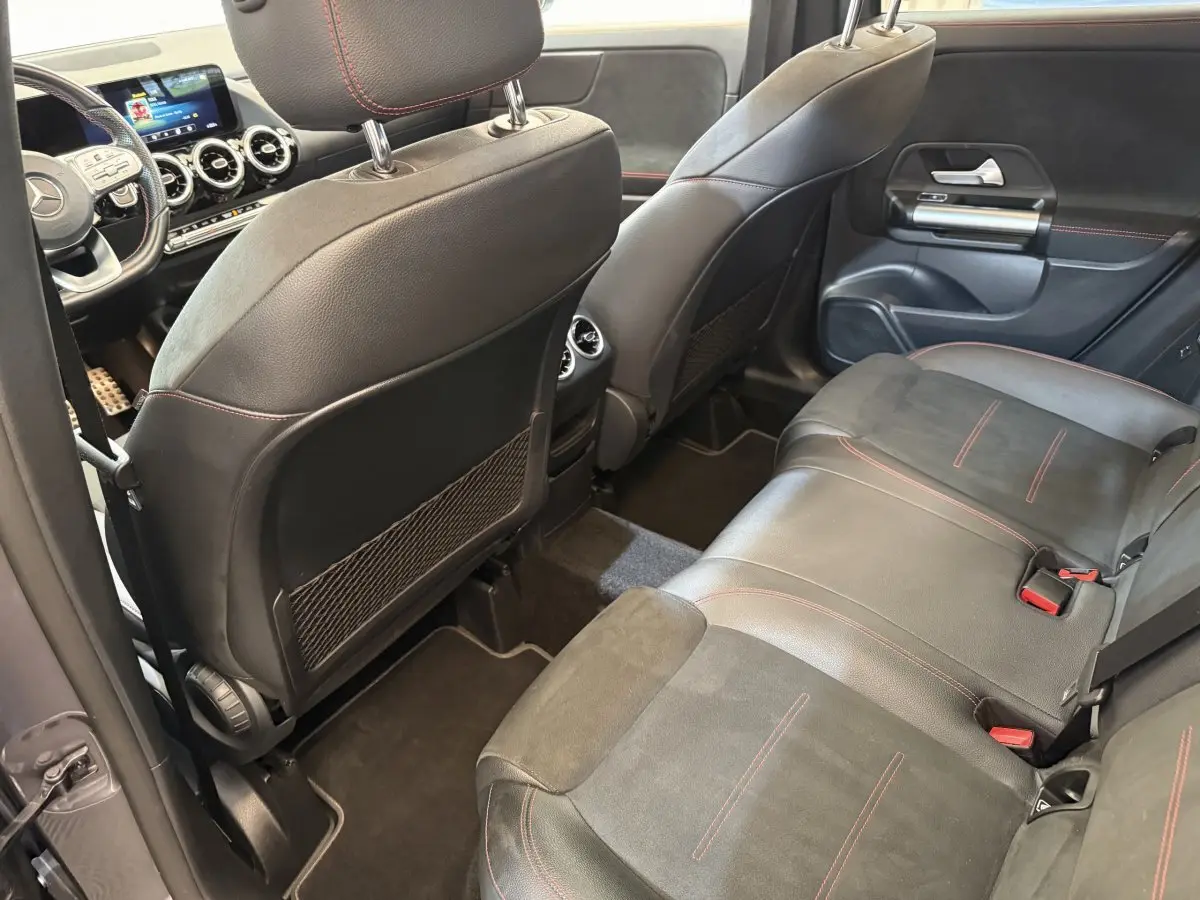 Vue intérieure arrière droite du Mercedes GLA 250 e AMG Line 2023, sièges cuir noir avec surpiqûres rouges et tableau de bord digital.