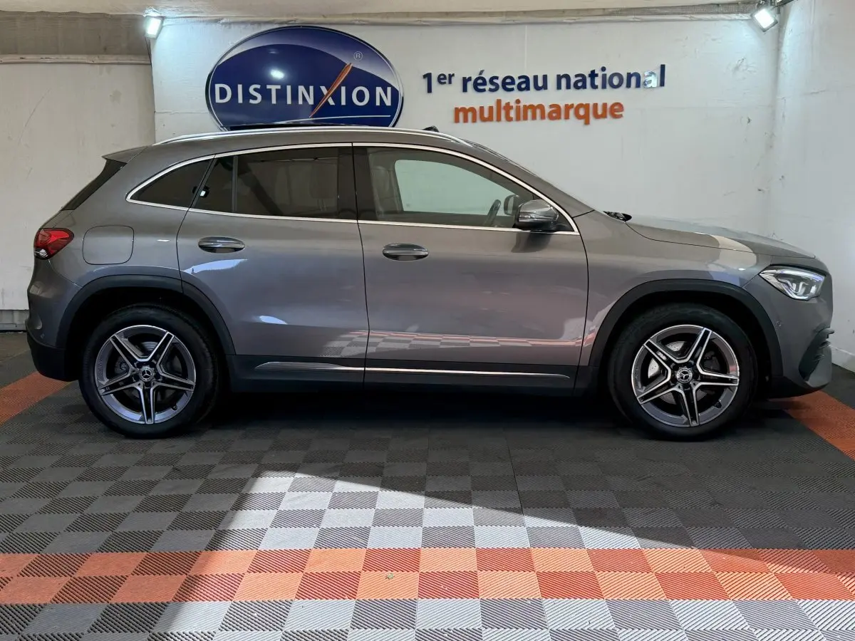 Vue de profil côté gauche d'une Mercedes GLA 250 e AMG Line hybride rechargeable gris clair, avec jantes alliage et rétroviseurs ton caisse.