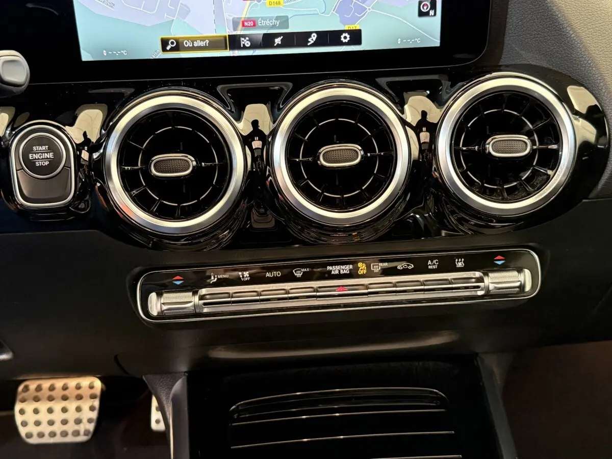 Vue rapprochée du tableau de bord noir du Mercedes GLA 250 e AMG Line 2023, avec aérateurs ronds chromés et écran tactile.