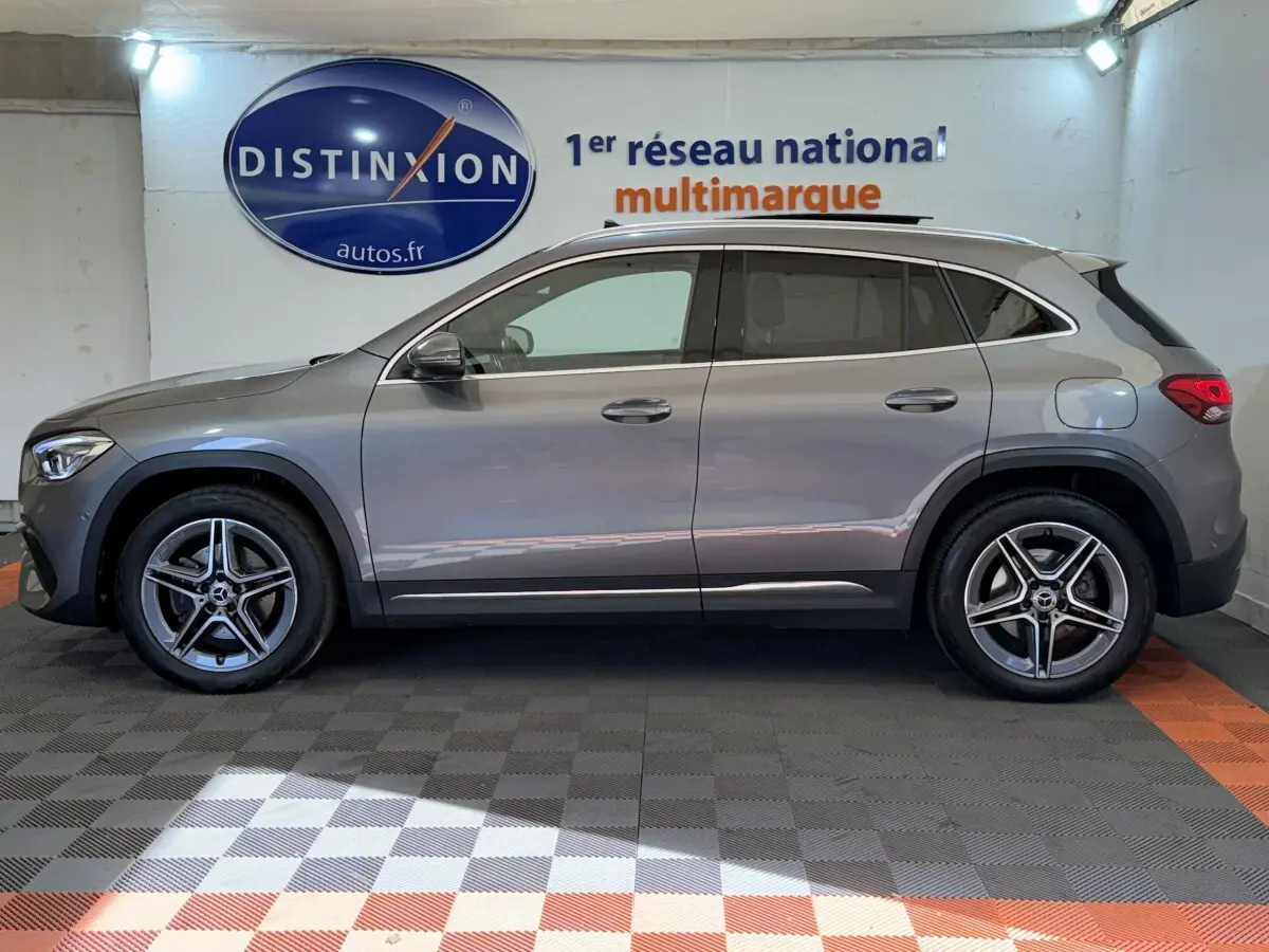 Vue de profil côté gauche d'un Mercedes GLA 250 e AMG Line gris clair hybride rechargeable dans un showroom.