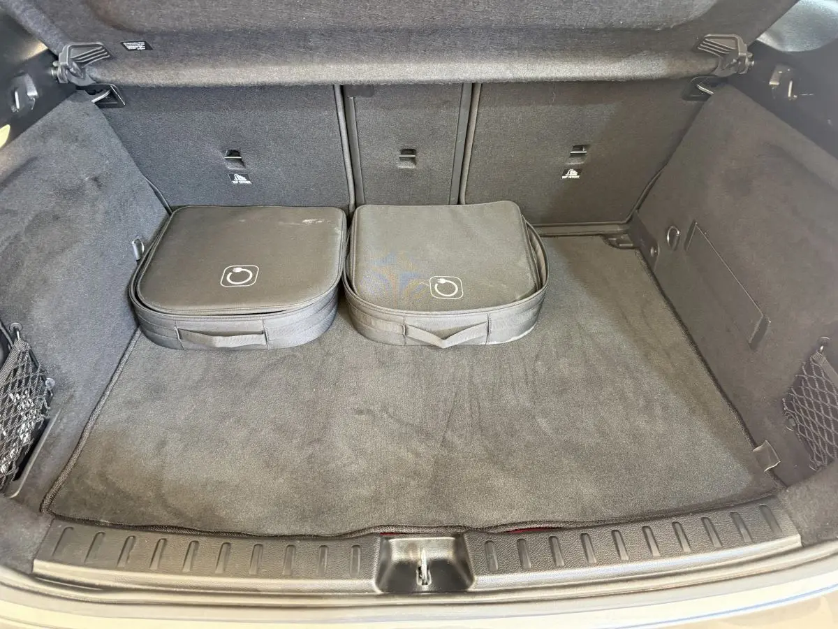 Coffre ouvert d’une Mercedes GLA 250 e AMG Line gris clair, vue intérieure avec deux sacs de rangement noirs.
