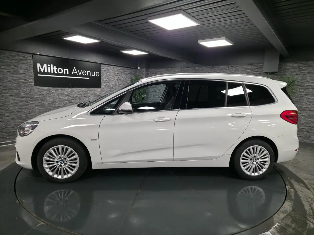 BMW Série 2 Gran Tourer blanc vue de profil gauche, jantes alliage 17'' et vitres teintées dans un showroom.