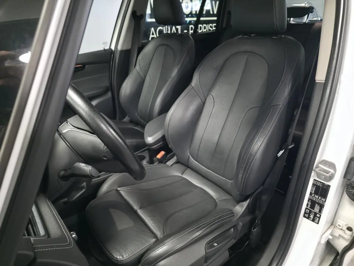Vue intérieure côté conducteur de la BMW Série 2 Gran Tourer 218d xDrive blanche avec sièges en cuir noir.