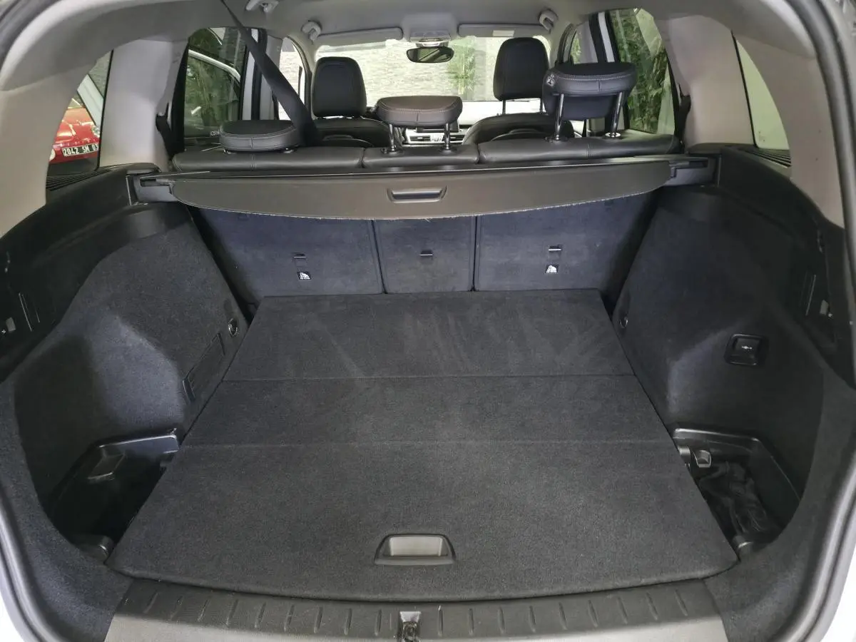 Vue arrière du coffre spacieux et plat de la BMW Série 2 Gran Tourer 218d xDrive blanc, avec banquette arrière rabattue.