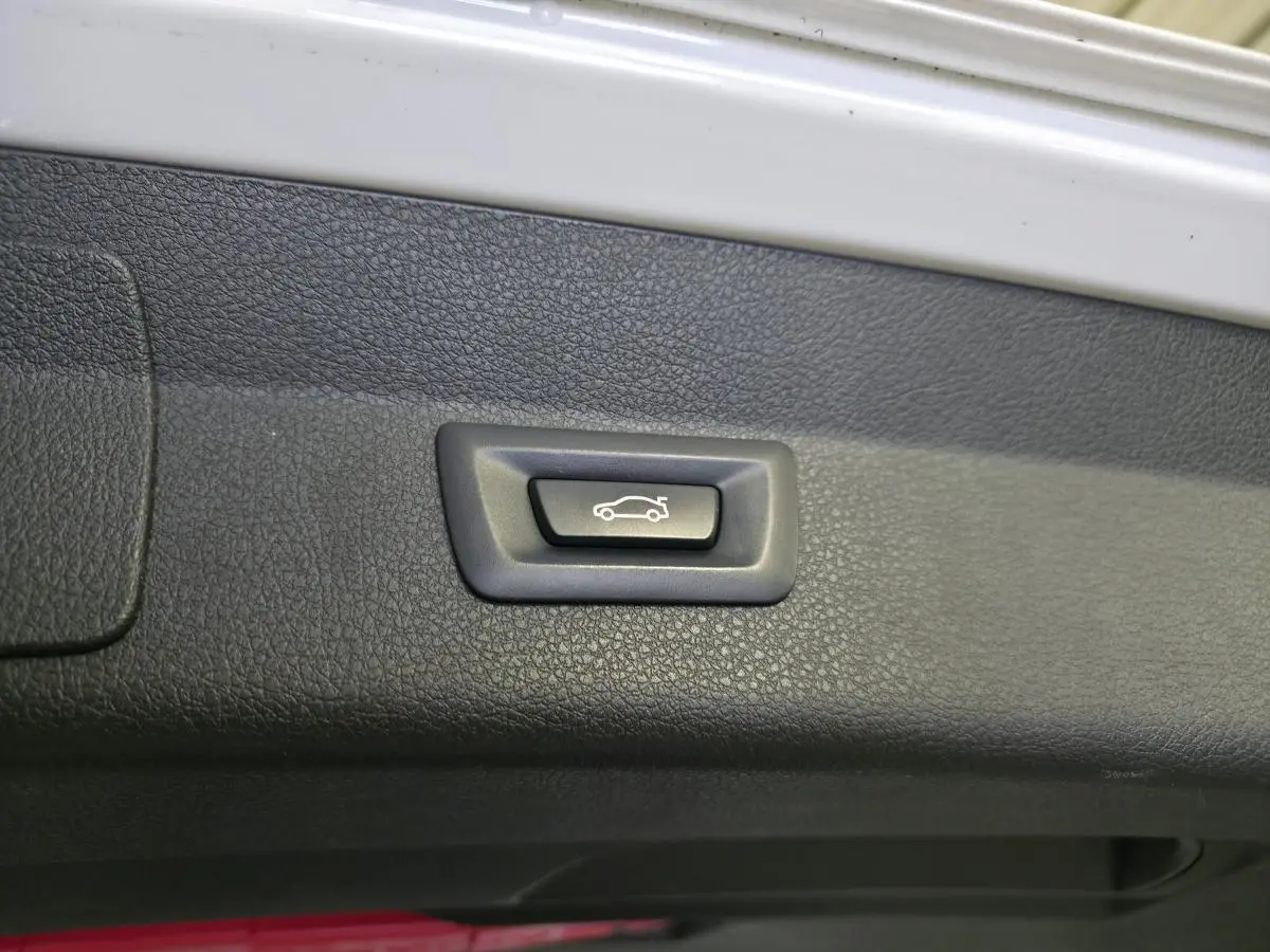 Bouton d'ouverture électrique du hayon sur la garniture intérieure noire d'une BMW Série 2 Gran Tourer blanche.